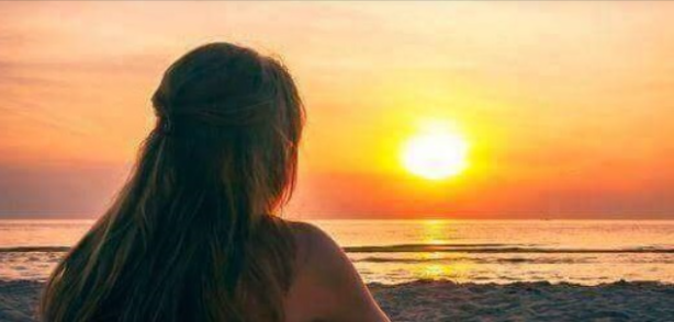 Silueta d'una dona d'esquena observant una posta de sol 